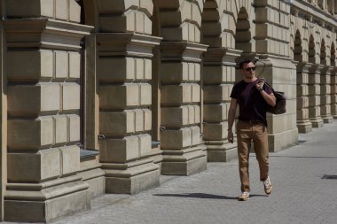 bir adam cadde boyunca bir çanta ile yürüyor