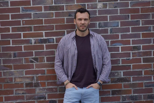 Un uomo sta al muro con una camicia — Foto Stock