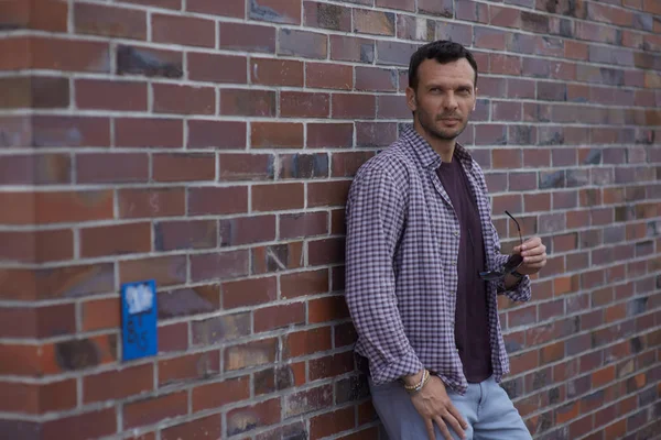 Un uomo sta al muro con una camicia — Foto Stock