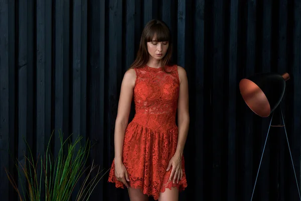 Girl in a red dress near the black wall — Stock Photo, Image