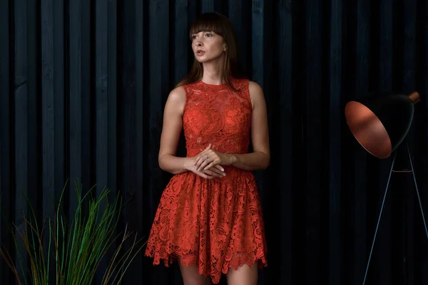 Menina em um vestido vermelho perto da parede preta — Fotografia de Stock