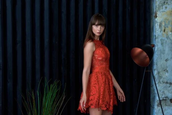 Menina em um vestido vermelho perto da parede preta — Fotografia de Stock