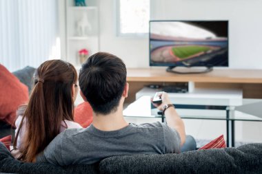 Arkadan görünüş Asya çift futbolda oturma odasında televizyon izliyor. Futbol Festivali kavramı.