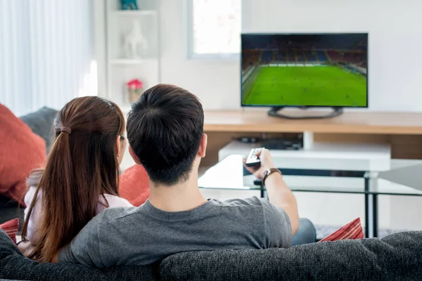 Arkadan görünüş Asya çift futbolda oturma odasında televizyon izliyor. Futbol Festivali kavramı.