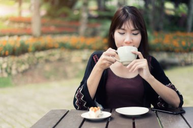 Asyalı kadınlar evde rahatlatıcı fincan kahve ve duygu yenileme ile Bahçe.