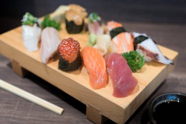 Siyah ahşap masa üzerinde ahşap plaka üzerinde yakın çekim suşi ve sashimi karışık. Japon yemekleri.