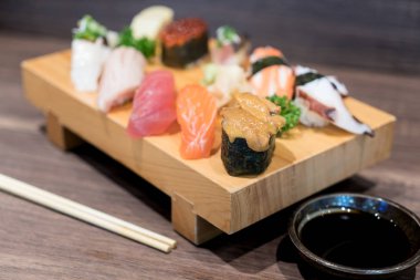 Siyah ahşap masa üzerinde ahşap plaka üzerinde yakın çekim suşi ve sashimi karışık. Japon yemekleri.