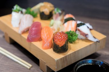 Siyah ahşap masa üzerinde ahşap plaka üzerinde yakın çekim suşi ve sashimi karışık. Japon yemekleri.