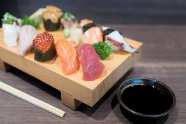 Siyah ahşap masa üzerinde ahşap plaka üzerinde yakın çekim suşi ve sashimi karışık. Japon yemekleri.