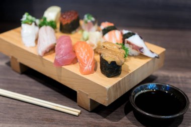 Siyah ahşap masa üzerinde ahşap plaka üzerinde yakın çekim suşi ve sashimi karışık. Japon yemekleri.
