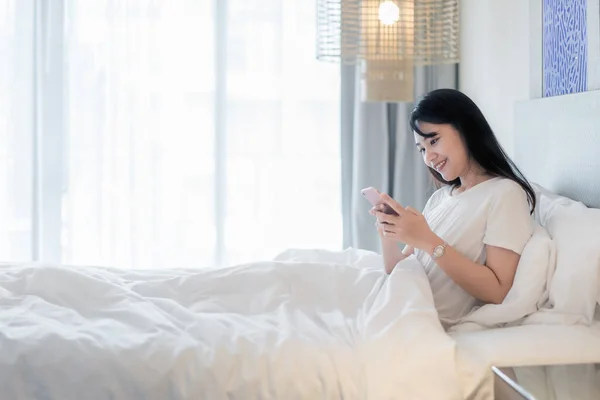 Bela Jovem Sorrindo Ásia Mulher Deitado Branco Cama Usando Telefone — Fotografia de Stock