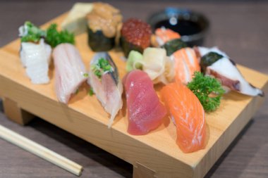 Siyah ahşap masa üzerinde ahşap plaka üzerinde yakın çekim suşi ve sashimi karışık. Japon yemekleri.