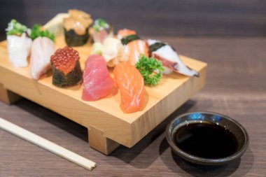 Siyah ahşap masa üzerinde ahşap plaka üzerinde yakın çekim suşi ve sashimi karışık. Japon yemekleri.
