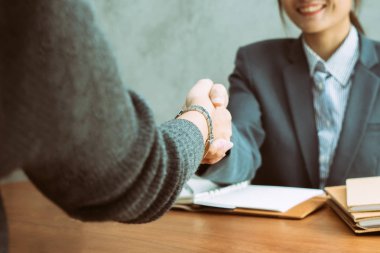 Onlar bir anlaşma yakın bir masa üzerinde el sıkışan iki Asya iş kadınları ya da ortaklık, odağı bir eller genç Asyalı kız