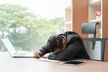 Masa başında iş ofisinde bir dizüstü bilgisayar üzerinde uyku overworked işadamı yorgun. Asya iş adamı