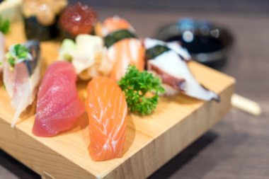 Siyah ahşap masa üzerinde ahşap plaka üzerinde yakın çekim suşi ve sashimi karışık. Japon yemekleri.
