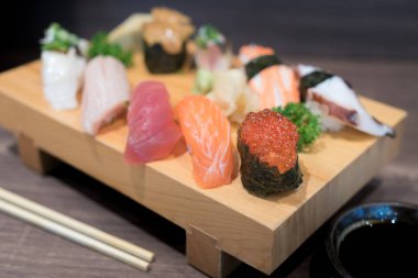 Siyah ahşap masa üzerinde ahşap plaka üzerinde yakın çekim suşi ve sashimi karışık. Japon yemekleri.