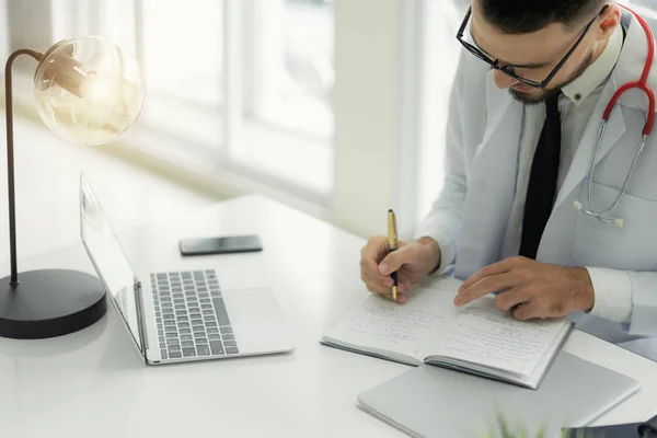 Arzt Arbeitet Mit Laptop Computer Und Schreibt Papierkram Mit Arztstethoskop — Stockfoto