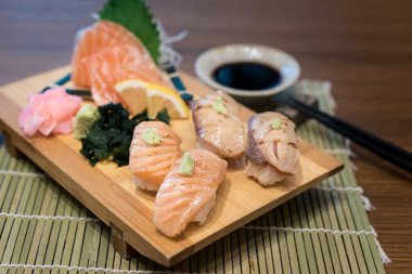 Karma somon suşi Japon sos ve yeşil yaprak dekorasyon, Japon yemekleri, birlikte ahşap plaka üzerinde yakın çekim suşi 