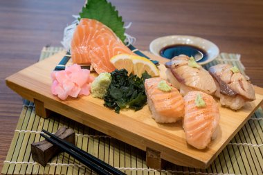 Karma somon suşi Japon sos ve yeşil yaprak dekorasyon, Japon yemekleri, birlikte ahşap plaka üzerinde yakın çekim suşi 
