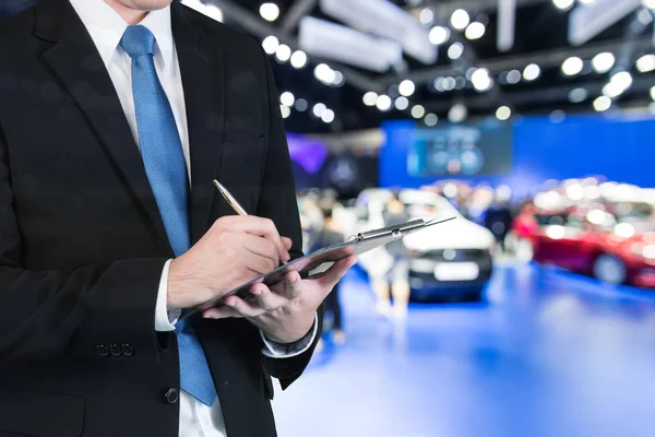 Yeni araba showroom Bayi yeni araba satın alma, görüntülenen arka plan bulanık ile ticaret rezervasyon holding saleman eller çift pozlama.