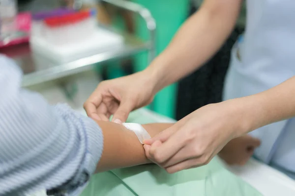 Enfermera aplicando vendaje en la mano del paciente después de análisis de sangre en hos —  Fotos de Stock