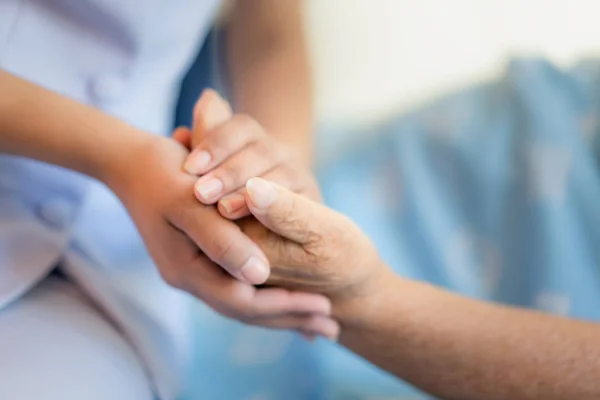 Infirmière assise sur un lit d'hôpital à côté d'une femme plus âgée aidant h — Photo