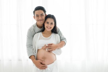 Yakışıklı Asyalı adam ve onun güzel hamile karısı bir sarılma vardır