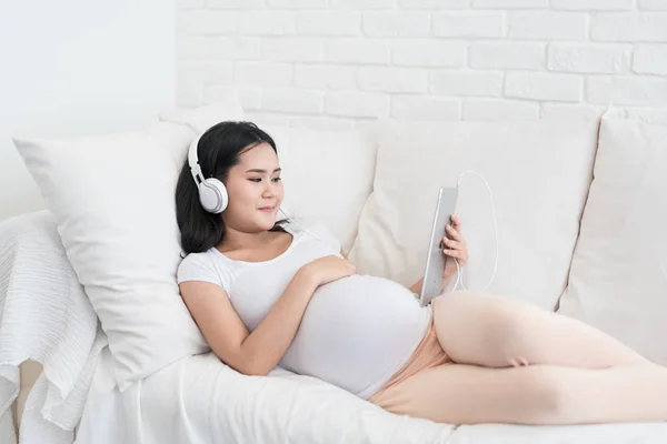 Портрет беременной азиатки, сидящей дома на диване и лисе — стоковое фото
