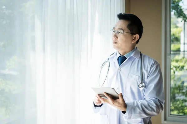 Azjatycki człowiek lekarz medyczny za pomocą komputera typu Tablet w szpitalu offic — Zdjęcie stockowe