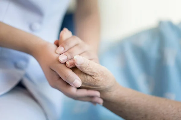 Infirmière assise sur un lit d'hôpital à côté d'une femme plus âgée aidant h — Photo