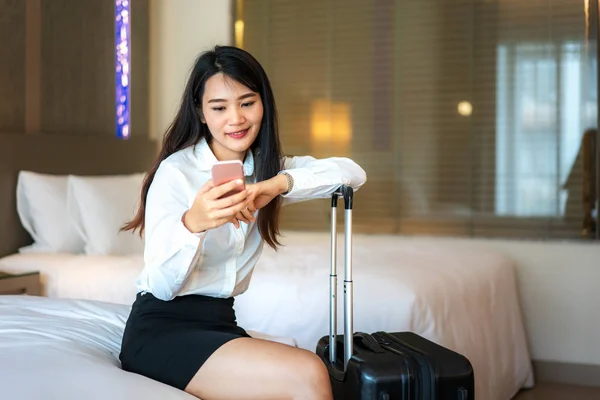 Asian woman reading phone messages in hotel room. Female executi