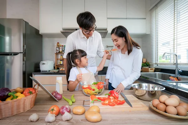 Asiática hijas alimentación ensalada a su madre y su padre stand — Foto de Stock