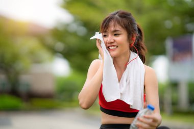 Asyalı güzel kadın tek başına antrenman yaptıktan sonra rahatlamak için oturuyor. 