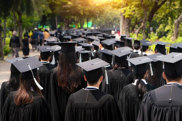 Rear view of group of university graduates in black gowns lines