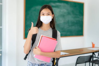 Asyalı ilkokul öğrencileri okula geri dönerken Covid 19 salgınını önlemek için maske takıyorlar. Eğitim konsepti için yeni bir normal.