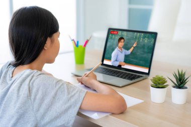 Asyalı kız öğrenci video konferansında öğretmenle evde bilgisayar başında e-öğrenme. Evde eğitim ve uzaklık öğrenimi, çevrimiçi, eğitim ve internet koruması COVID-19 virüslerinden.