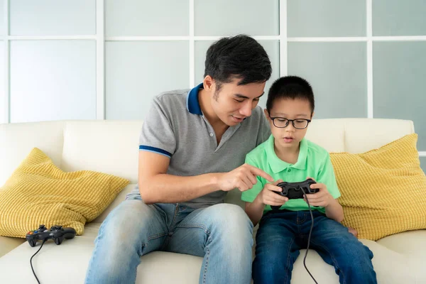 Азиатский Отец Семьи Обучает Своего Сына Играть Видеоигры Джойстиками Сидя — стоковое фото