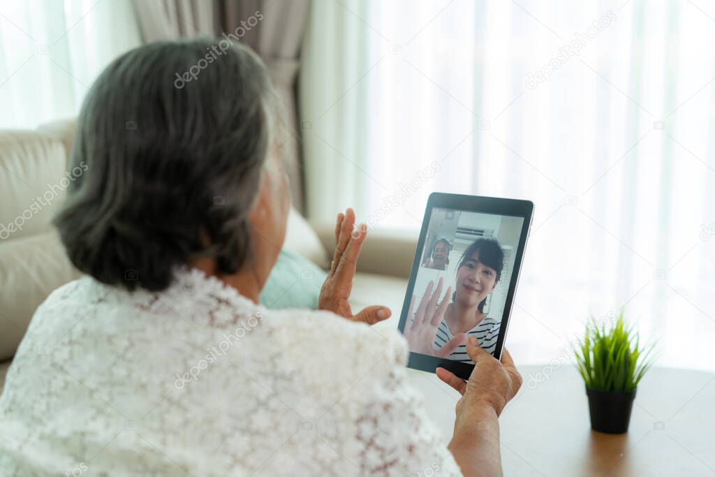 Asian elderly woman virtual happy hour meeting and talking online together with her daughter in video conference with tablet for a online meeting in video call for social distancing