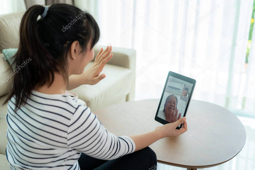 Asian young woman virtual happy hour meeting and talking online together with her mother in video conference with digital tablet for a online meeting in video call for social distancing