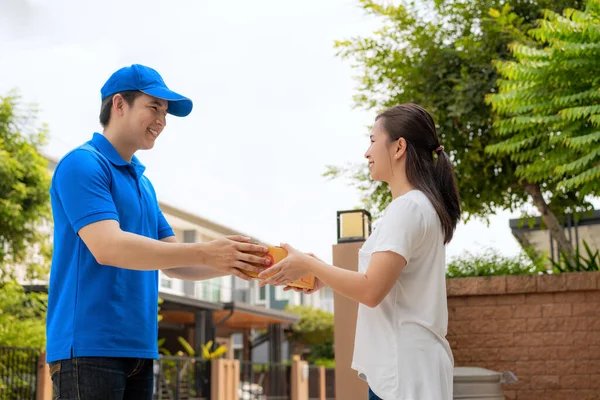 Asiatischer Lieferjunge Blauer Uniform Lächelt Und Hält Einen Karton Vor — Stockfoto