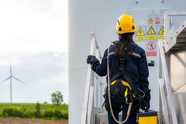 Asian woman Inspection engineer preparing and progress check of a wind turbine with safety in wind farm in Thailand.