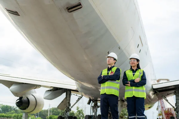 亚洲男子和妇女工程师维修飞机臂架交叉 从机场维修 现代化和翻新的角度出发 将扳手握在飞机前部 — 图库照片