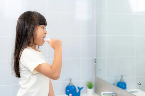 Carino Asiatico Scuola Primaria Ragazza Lavarsi Denti Guardando Nello Specchio — Foto Stock