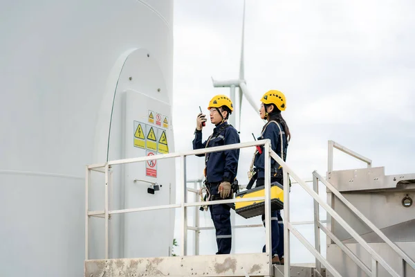 Asian man and woman Inspection engineers preparing and progress check of a wind turbine with safety in wind farm in Thailand.