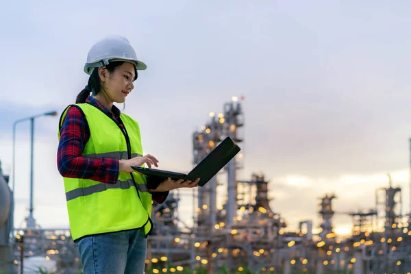ノートブックで夜に働くアジアの女性石油化学エンジニア検査官の安全品質管理のために夜の石油 ガス精製プラント産業工場内 — ストック写真
