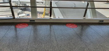 Covid 19 Coronavirus 'a bağlı olarak havalimanından uzak durmak için yerde kırmızı ayak izleri var.