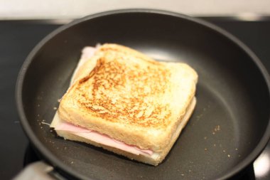 Siyah tavada pişirilmiş jambonlu ve peynirli sandviç.