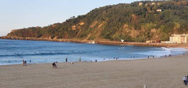 Donostia San Sebastian, Guipuzcoa, Pais Vasco, İspanya: 22 Eylül 2020: İnsanlar gün batımında Gros sahilinde sörf yapıyor ve yürüyor.
