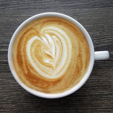 Bir fincan kahve latte sanat siyah arka plan üzerine yukarıdan.